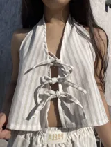 Top beige a rayas verticales, con escote halter y lazos ajustables en el frente y la espalda.