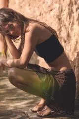 Falda corta de tiro medio confeccionada en tejido de encaje color marrón, con diseño evasé y detalle de aplicación de tachas metálicas en la cintura y el ruedo.