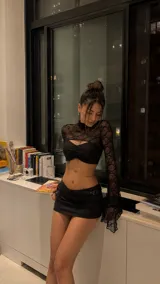Top de encaje negro con cuello alto y mangas largas acampanadas, que incluye un corpiño tipo strapless integrado con fruncido central.