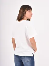 Remera de algodón blanca con cuello redondo y mangas cortas. Presenta un estampado frontal con la palabra 'VENICE' en letras rojas y la frase 'Italy, Amore' en cursiva debajo.