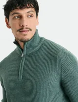 Sweater de punto inglés color verde, con cuello alto y cierre frontal parcial metálico. Diseño de manga larga con puños y ruedo acanalados.