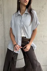 Camisa de manga corta con diseño a rayas celestes y blancas, cuello clásico y cierre frontal de botones.