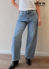 Jeans de denim azul claro con corte balloon fit, silueta amplia en las piernas y costuras curvas decorativas en el frente.