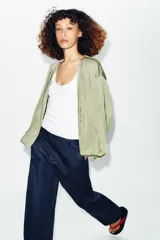 Cazadora bomber fluida de color verde, con cuello redondo, manga larga abullonada, bolsillos frontales y cierre de cremallera metálica.