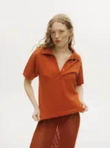 Remera tipo chomba de punto color negro, con escote en V abotonado y detalles de terminación en crochet en el cuello, mangas y ruedo.