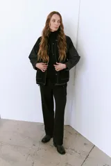 Campera color caramelo con mangas de denim azul oscuro. Presenta cuello alto, cierre frontal con botones, cuatro bolsillos delanteros con solapa y pespuntes blancos decorativos.