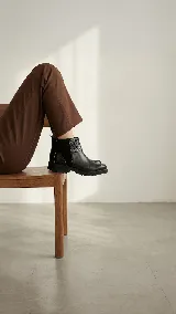 Bota corta de cuero color marrón, con diseño que combina cuero liso y sectores con textura grabada. Presenta una base robusta con taco medio y cierre lateral para facilitar el calce.