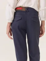 Pantalón de vestir azul marino, corte cigarette con pierna angosta y abertura en el bajo. Presenta costuras en contraste color beige y un botón marrón en la cintura.