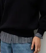 Buzo de tricot con cuello redondo y puños ajustados. Presenta un diseño de calce holgado y tejido de punto liso.