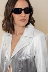 Chaqueta corta de cuero ecológico con diseño degradado de blanco a gris. Tiene cuello tipo solapa, cierre frontal asimétrico con broche y bolsillos con cierre.