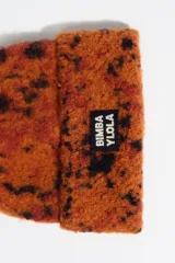 Gorro tipo beanie de punto con textura peluda y estampado animal print de lince en tonos naranja y negro. Presenta un parche frontal con el logo de la marca.