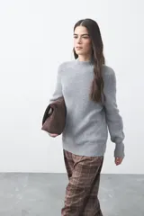 Polera de tejido de punto acanalado en color gris, con cuello alto y mangas largas con puños ajustados. Presenta un diseño de silueta relajada y estructura minimalista.