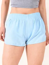 Short deportivo de tela técnica, color celeste, con cintura elástica y diseño de corte curvo en los laterales.