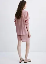 Camisa de lyocell color rosado con diseño a rayas sutiles, de corte recto, con cuello camisero, manga larga y cierre frontal de botones.