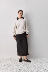 Sweater negro de tejido suave con escote redondo, mangas largas y calce relajado, con terminaciones acanaladas en cuello, puños y ruedo.