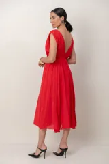 Vestido largo rojo de corte griego, sin mangas, con escote en V profundo, falda amplia y detalles de encaje.