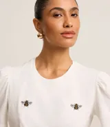 Blusa blanca de algodón con cuello redondo, mangas cortas abullonadas y bordados de abejas.