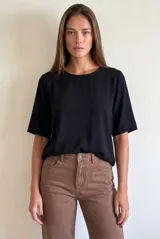 Blusa negra de manga corta y cuello redondo, confeccionada en tejido ligero y fluido.