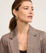 Blazer marrón con estampado de cuadros, confeccionado en punto roma. Tiene solapa en el cuello, cierre con un botón, bolsillos delanteros y corte entallado.