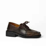 Zapato acordonado de cuero vacuno con acabado desgastado, de horma cuadrada y suela de goma con pequeño taco.