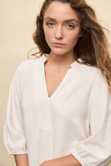 Vestido corto negro de silueta relajada, con escote en V y mangas 3/4 levemente abullonadas.