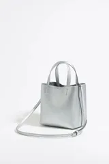 Bolso de mano pequeño color plateado, marca Bimba y Lola, modelo Chihuahua. Con doble asa de mano, asa larga ajustable y bolsillo interior con cremallera. Exterior personalizado con logo metálico.