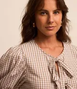 Blusa de tricolina de algodón con estampado de cuadros vichy, mangas cortas abullonadas, cuello redondo, abertura delantera con lazos y recorte fruncido en la cintura.