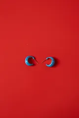 Aros tipo argolla semicircular de acetato color azul con lunares rojos estampados.