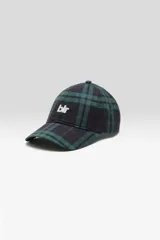 Gorra estilo béisbol de seis paneles con visera curva, confeccionada en tejido con estampado a cuadros en tonos verde oscuro y negro. Cuenta con el logo de la marca bordado en color blanco en el frente y cierre ajustable en la parte trasera.