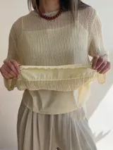 Sweater de punto calado color rosado, con diseño holgado, cuello redondo y mangas largas, que incluye una musculosa interior con terminación bordada en el bajo.