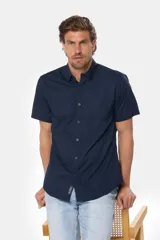 Camisa lisa de manga corta color azul marino, con cuello clásico, cierre de botones frontales y un bolsillo en el pecho. Confeccionada 100% en algodón.