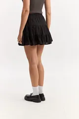 Falda corta blanca con volados en capas, confeccionada en tejido de algodón con bordado estilo broderie. Cuenta con cintura elástica.
