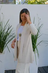 Saco abierto tipo cárdigan color crudo, de corte recto y largo medio, con mangas largas y dos bolsillos frontales aplicados.