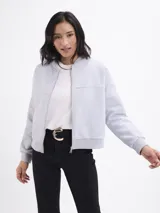 Campera tipo bomber de felpa color gris claro, con cierre frontal completo, cuello redondo y puños elásticos acanalados.