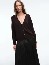 Cardigan de punto color marrón oscuro, con escote en V, manga larga y cierre frontal con botones metálicos dorados.