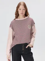 Remera de manga larga con diseño a rayas horizontales en tonos celestes y blancos en el cuerpo, y mangas a rayas azul marino y blancas. Presenta cuello redondo en color azul marino, logo bordado en el pecho y calce holgado.