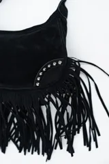 Cartera de hombro tipo hobo confeccionada en gamuza negra, con diseño de flecos largos en la parte inferior y detalles de tachas metálicas plateadas en los laterales.