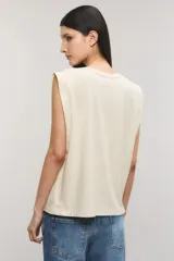 Musculosa de jersey de algodón color blanco, sin mangas, con hombreras y estampa frontal fotográfica en tonos grises, rojos y amarillos con la inscripción "Kate Mess" y detalles de tachas.