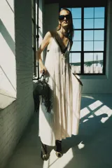 Vestido midi de satén color crudo, con escote en V, tirantes finos y detalle de lazada en el delantero.