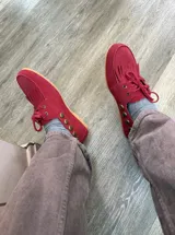 Náuticos de gamuza color rojo con flecos en la parte delantera, cordones al tono y detalle de tachas metálicas en los laterales.