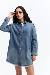 Vestido tipo camisa de jean con calce holgado, cuello clásico, cierre frontal con botones y ruedo con terminación desflecada.