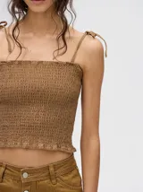 Top crop de tela denim con efecto fruncido, breteles finos ajustables con lazos y diseño entallado al cuerpo.