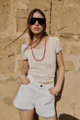 Shorts de jean tiro medio, corte mom fit, con bajo deshilachado y forro de bolsillos delanteros estampado a cuadros que asoma por debajo.