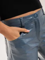 Pantalón de jean elastizado azul con terminación metalizada, corte wide leg, tiro medio, cierre delantero con botón, bolsillos laterales y traseros.