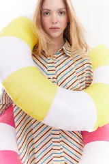 Camisa oversize de algodón con estampado de rayas multicolor en distintas direcciones, cuello camisero, mangas largas y detalle de botonera vertical en la espalda.