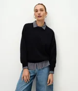 Buzo de tricot con cuello redondo y puños ajustados. Presenta un diseño de calce holgado y tejido de punto liso.