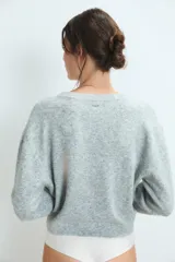Sweater de punto gris con diseño de corazón blanco en el pecho, cuello redondo y mangas largas.