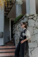 Jean negro de corte recto y tiro alto, con detalle de botones en el dobladillo de las piernas.