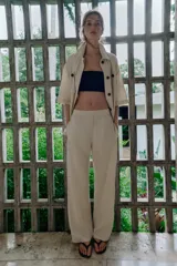 Pantalón de tiro medio confeccionado en lino color beige, de pernera recta con nervios marcados en el delantero. Posee bolsillos frontales, falsos bolsillos de vivo en la espalda y cierre frontal con cremallera, botón interior y gancho.