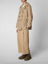 Campera trench corta color beige, con doble abotonadura frontal, cuello solapa y bolsillos laterales.
